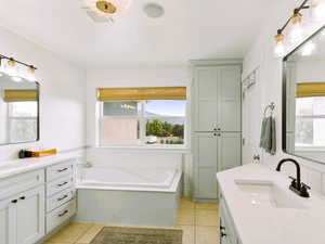 Master bath with double vanities, soak tub, private toilet & extra cabinets, walk in closet