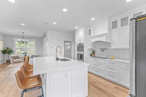 Kitchen featuring white cabinetry, decorative backsplash, stainless steel appliances, recessed lighting, and a breakfast bar area