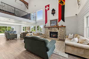 Living room with a towering ceiling, wood finished floors, a fireplace, and wood walls