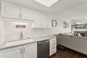 Kitchen featuring open floor plan, stainless steel dishwasher, tasteful backsplash, and dark wood finished floors