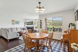 Dining room featuring a warm lit fireplace, a chandelier, and dark wood-style flooring