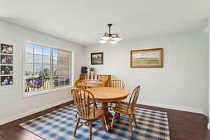 Dining space with a chandelier and dark wood-style floors
