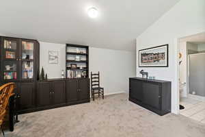 Office with vaulted ceiling and carpet flooring