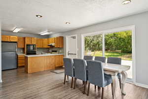 Dining area featuring light wood-style floors, a textured ceiling, and recessed lighting