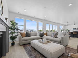 Living area with healthy amount of natural light, a textured ceiling, light wood-style flooring, and recessed lighting