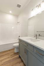 Full bath featuring vanity, washtub / shower combination, wood finished floors, and recessed lighting