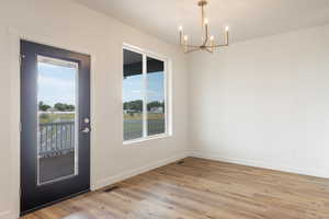Unfurnished room with a chandelier, plenty of natural light, and light wood finished floors