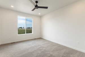Carpeted spare room featuring ceiling fan and recessed lighting