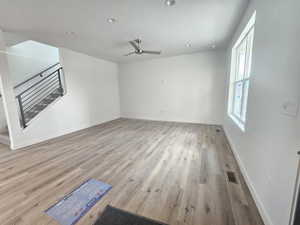 Empty room featuring stairs, a ceiling fan, wood finished floors, and recessed lighting