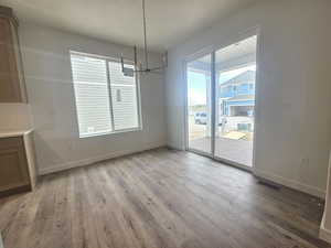 Unfurnished dining area featuring a chandelier and light wood-style flooring