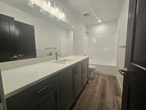Bathroom with wood finished floors, vanity, tub / shower combination, and recessed lighting