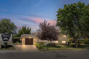 View of front of house featuring an attached garage, concrete driveway, and a front lawn