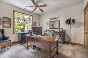Office area featuring a ceiling fan and light carpet