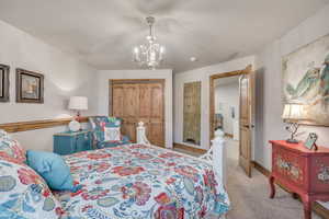 Bedroom featuring light carpet, a chandelier, and a closet