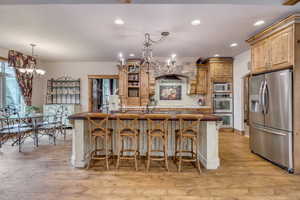 Kitchen featuring a chandelier, appliances with stainless steel finishes, light wood-style flooring, recessed lighting, and decorative backsplash