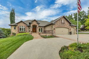 View of front of house featuring stone siding, a front lawn, a garage, roof with shingles, and concrete driveway