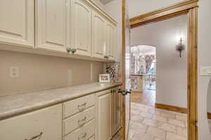 Kitchen with cream cabinetry, arched walkways, light countertops, a chandelier, and light stone finish floors