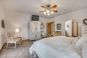 Bedroom featuring arched walkways, carpet flooring, and a ceiling fan