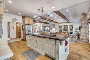Kitchen with light wood finished floors, recessed lighting, an island with sink, a chandelier, and arched walkways