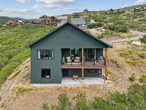 Rear view of property featuring a patio area, a balcony, and board and batten siding