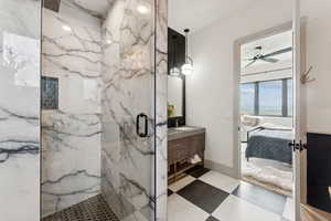 Full bathroom featuring a marble finish shower, ensuite bathroom, vanity, and a ceiling fan