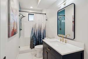 Full bathroom with vanity, tiled shower, and tile patterned flooring