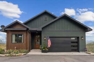 View of front facade with an attached garage, board and batten siding, and driveway
