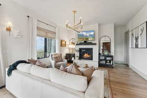 Living room with a chandelier, light wood-style floors, and a glass covered fireplace