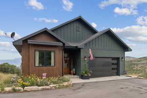 View of front of property with a mountain view, a garage, board and batten siding, and driveway