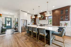 Kitchen featuring light countertops, beverage cooler, tasteful backsplash, stainless steel refrigerator with ice dispenser, and open shelves