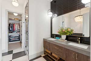 Full bath featuring tile patterned floors, double vanity, a walk in closet, and a shower stall