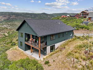 Back of house featuring a shingled roof, a mountain view, and a patio area