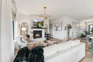Living area with a chandelier, light wood-type flooring, and a glass covered fireplace