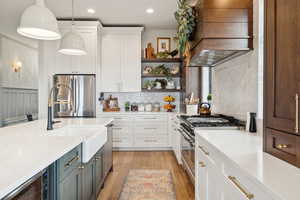 Kitchen featuring light countertops, white cabinetry, stainless steel appliances, decorative backsplash, and recessed lighting