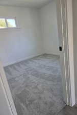 Unfurnished room featuring baseboards and light carpet