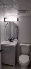 Half bathroom featuring vanity and a textured ceiling