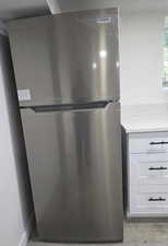 Kitchen view of freestanding refrigerator and light stone counters