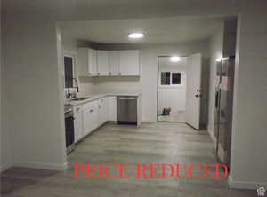 Kitchen featuring light countertops, white cabinets, light wood-style floors, and stainless steel appliances
