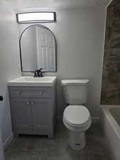 Full bath with a textured ceiling and vanity