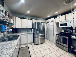 Kitchen featuring stainless steel appliances, tasteful backsplash, light countertops, white cabinets,