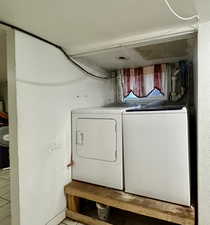 Washroom with washer and clothes dryer and light tile patterned floors