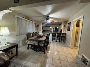 Dining space with ceiling fan, light tile patterned floors, and a textured ceiling