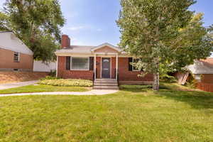 View of front of home featuring a chimney and brick siding