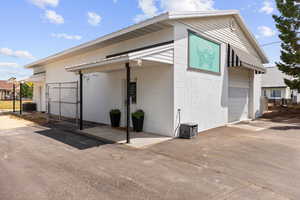 View of side of property featuring a garage, concrete block siding, concrete driveway, and a gate