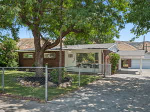 Brick rambler with a fully fenced front yard with beautiful shade.