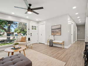 Living room with ceiling fan, light wood-style floors, and recessed lighting