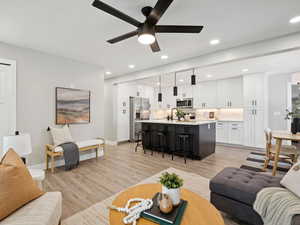 Living room with ceiling fan, light wood-style floors, and recessed lighting