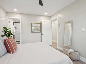 Primary bedroom featuring wood finished floors, recessed lighting, a ceiling fan, ensuite bathroom and walk in closet