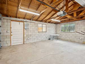 Garage featuring concrete block, garage door opener, and electric panel with 220 amps