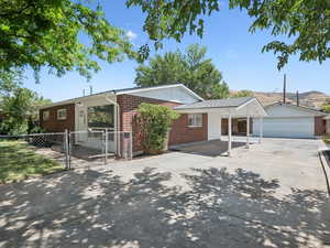 Ranch-style home featuring brick siding, a detached garage, carport and tons of parking